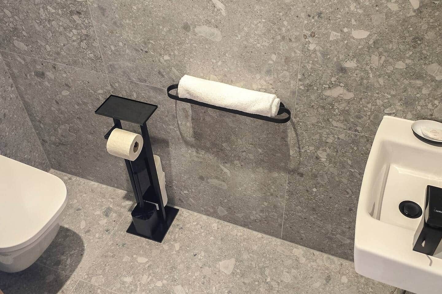 Un baño con inodoro, dispensador de toallas de papel y lavamanos.