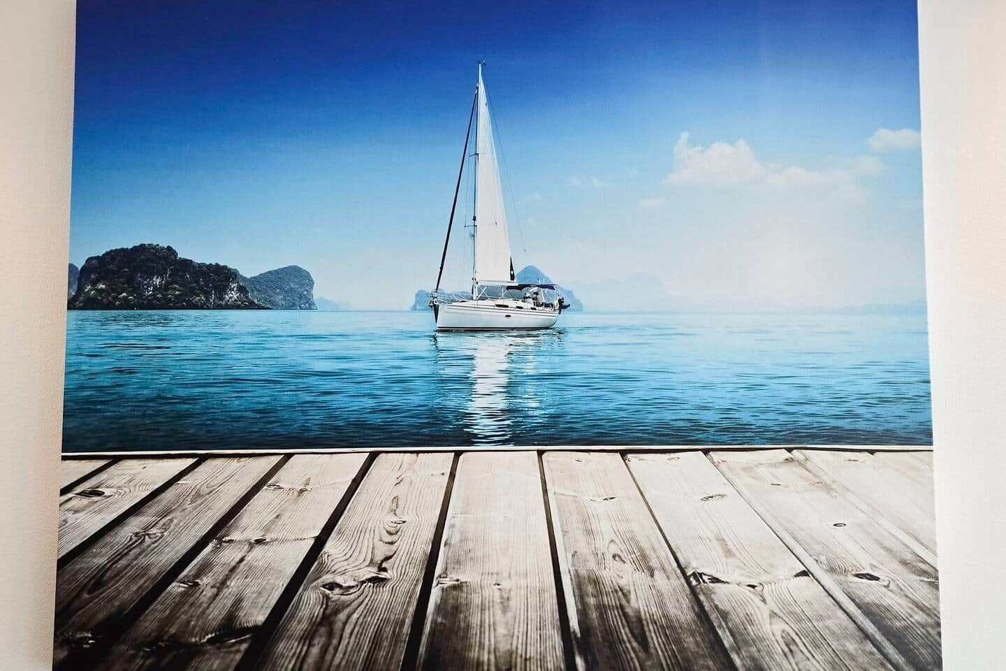 Um deck de madeira com um veleiro em águas calmas.