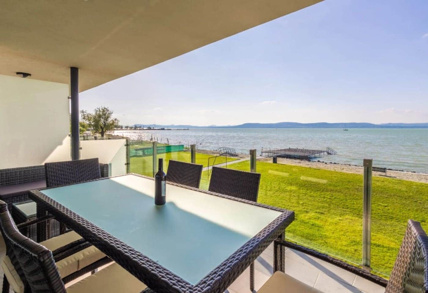 Un balcon avec une table et des chaises donnant sur une étendue d’eau.