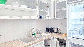 A modern kitchen with white cabinetry, a built-in sink, and a refrigerator with a MultiBox XXL compartment. - IMCT - Central Vibe Apartments 3 (Budapest)