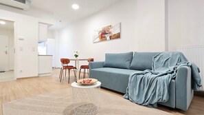 A modern living room with a sofa, a coffee table, and a dining area with chairs and a table. - IMCT - Central Vibe Apartments 3 (Budapest)