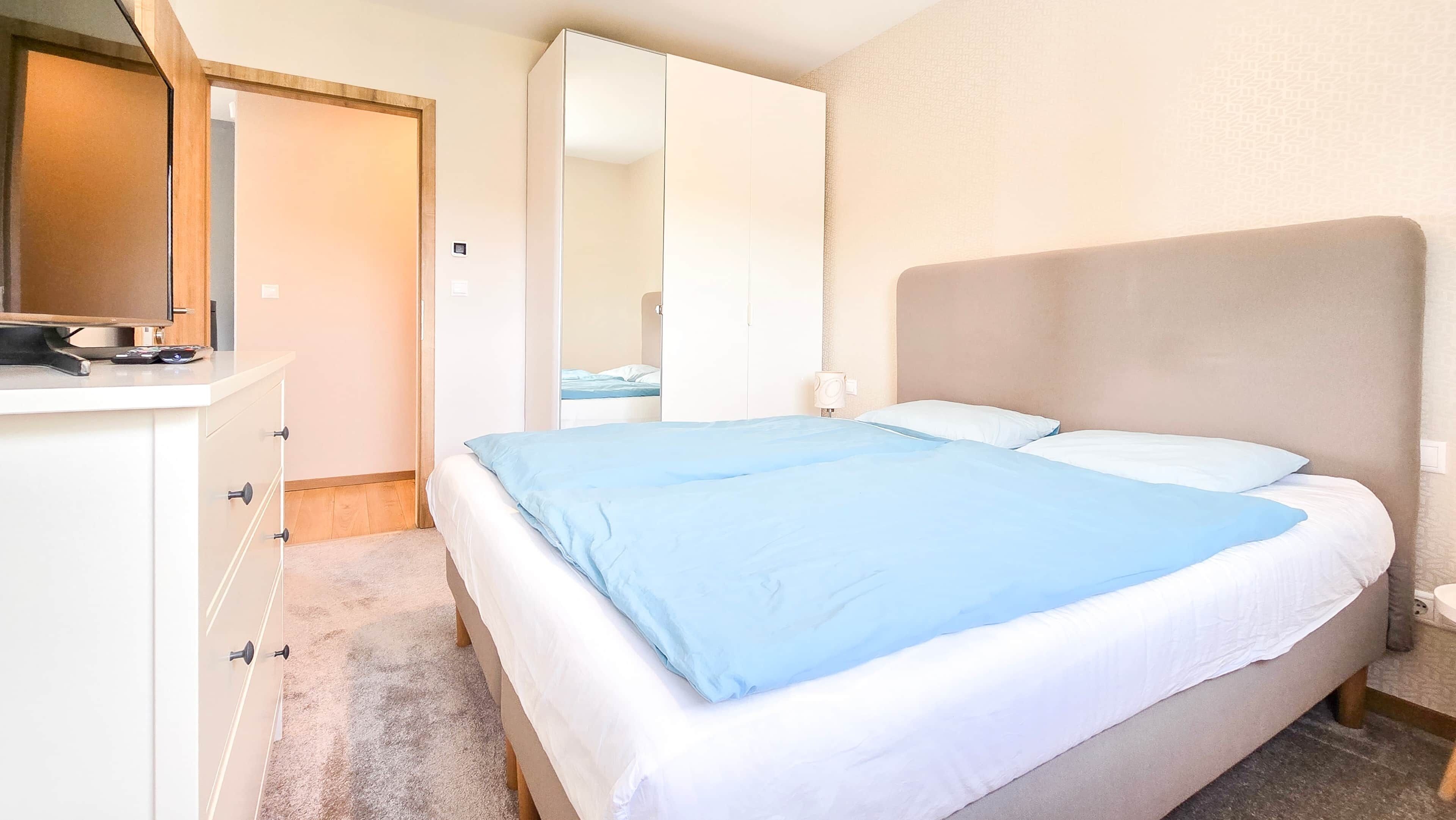 A bedroom with a bed, a dresser, and a mirror.