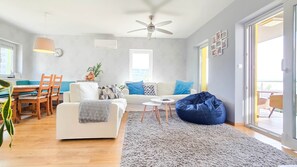 A living room with a sofa, coffee table, bean bag, and a ceiling fan. - LB - Apartman Mabelu (Siófok)