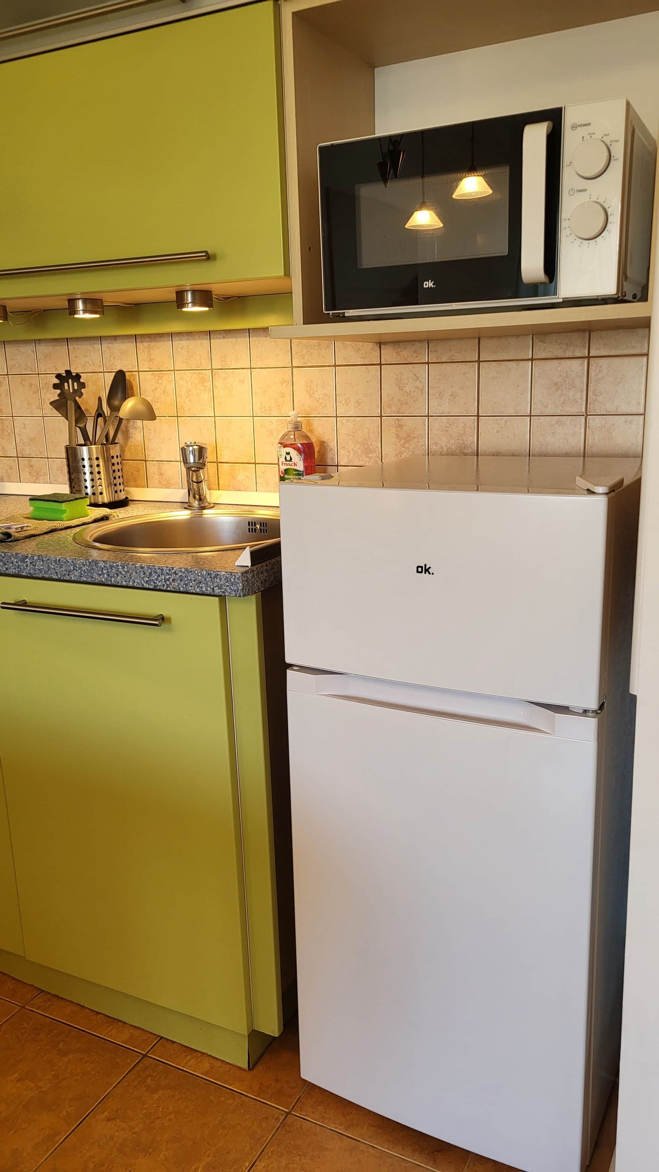 Uma cozinha com micro-ondas, geladeira e pia.