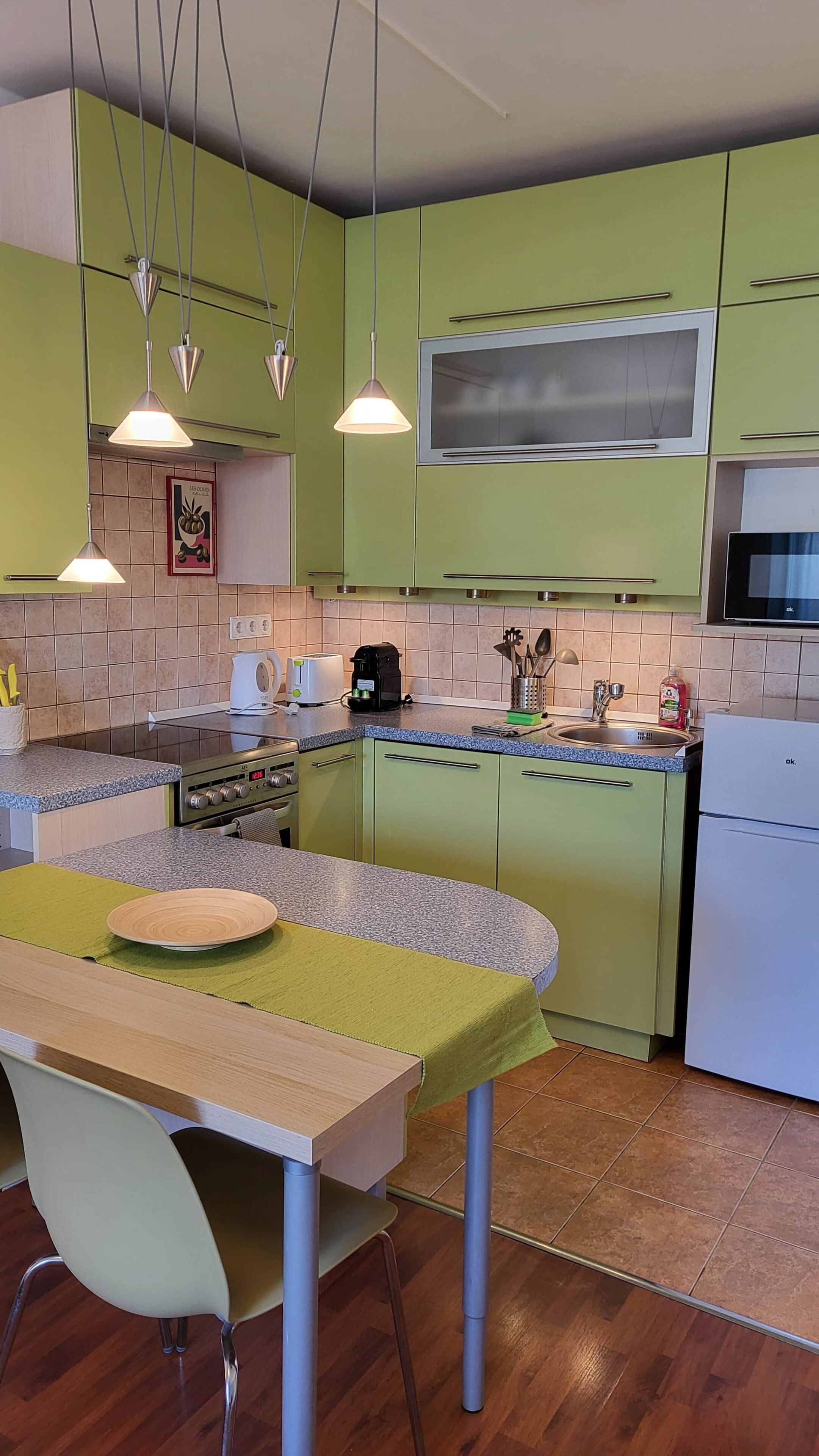 A kitchen with green cabinets, a microwave, a stove, and a sink.