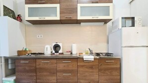 A kitchen with wooden cabinets, a microwave, a kettle, and a sink. - IMCT - MSpirit Apartman A Budapest (Budapest)