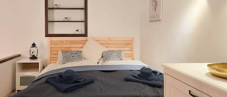 Un dormitorio con cama, mesitas de noche, un estante en la pared, una lámpara de noche y un adorno mural.