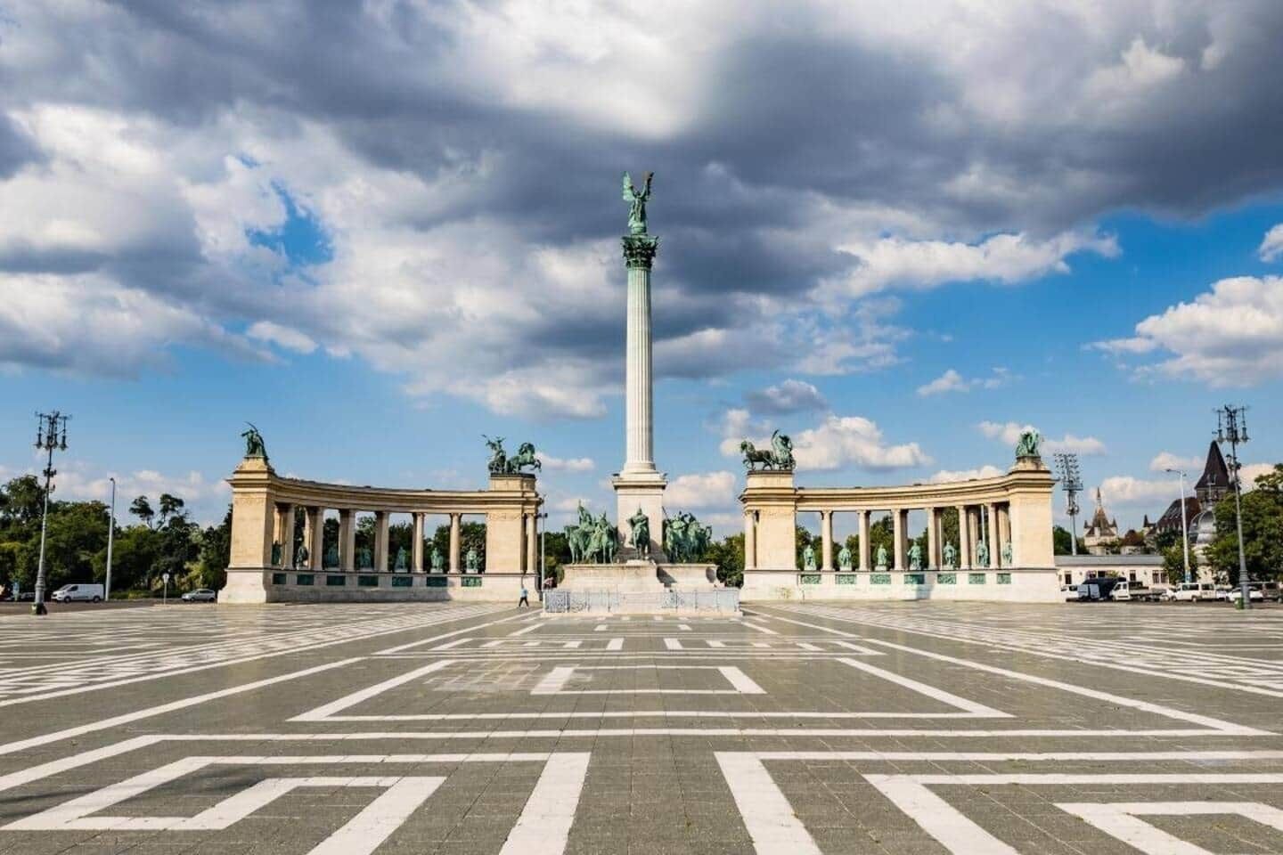 A wide open plaza with a central monument flanked by two symmetrical structures with columns.