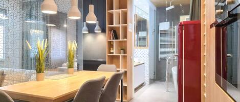 Un intérieur moderne avec un coin repas, des étagères en bois et des luminaires suspendus.
