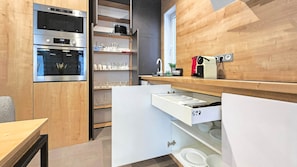 A modern kitchen with built-in appliances, a wooden wall, and a countertop with a sink and storage. - IMCT- WOODnest Home with A/C (Budapest)