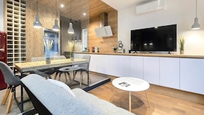 A modern living room with a sofa, a dining table, and a TV mounted on the wall. - IMCT- WOODnest Home with A/C (Budapest)