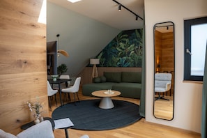 A modern living room with a round coffee table, a sofa, and a dining area with chairs. - IMCT - Urban Jungle Apartments 06 (Budapest)