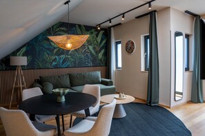 A modern living room with a round table, a sofa, and a hanging light fixture.