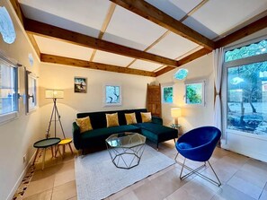A modern living room with a green sofa, a glass coffee table, and a blue chair. - Le Clos des Rosiers - Maison de charme (Fouras)