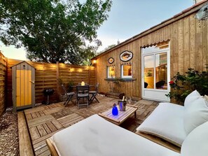 A wooden deck with outdoor furniture, a barbecue grill, and a dining area with chairs and a table. - Le Clos des Rosiers - Maison de charme (Fouras)