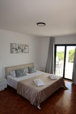 A bedroom with a bed, a painting, a window, and a view of the outdoors. - Villa Irene 7 Bed Villa close to Marina (Vilamoura)