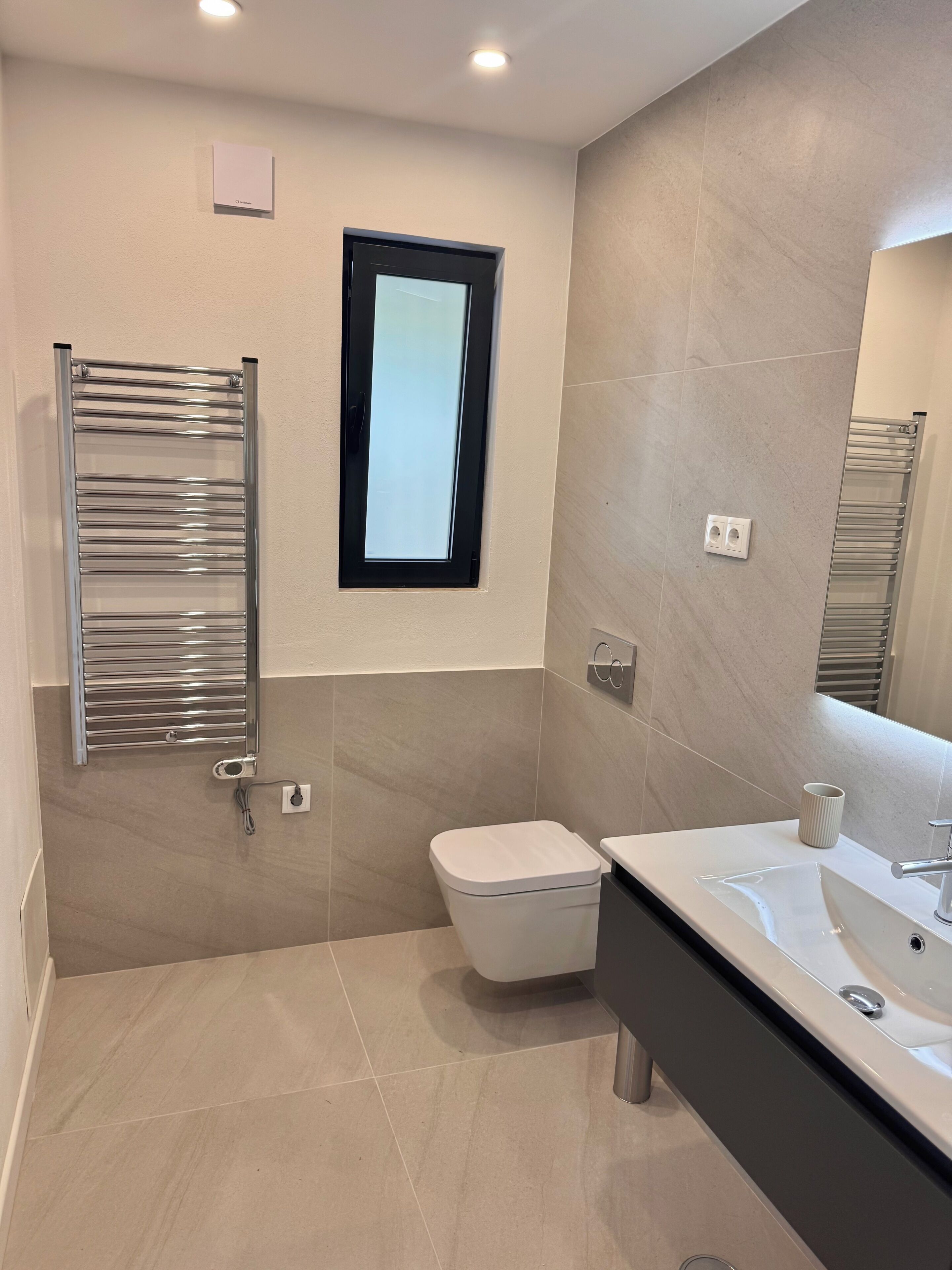 A modern bathroom with a toilet, sink, and towel rack.