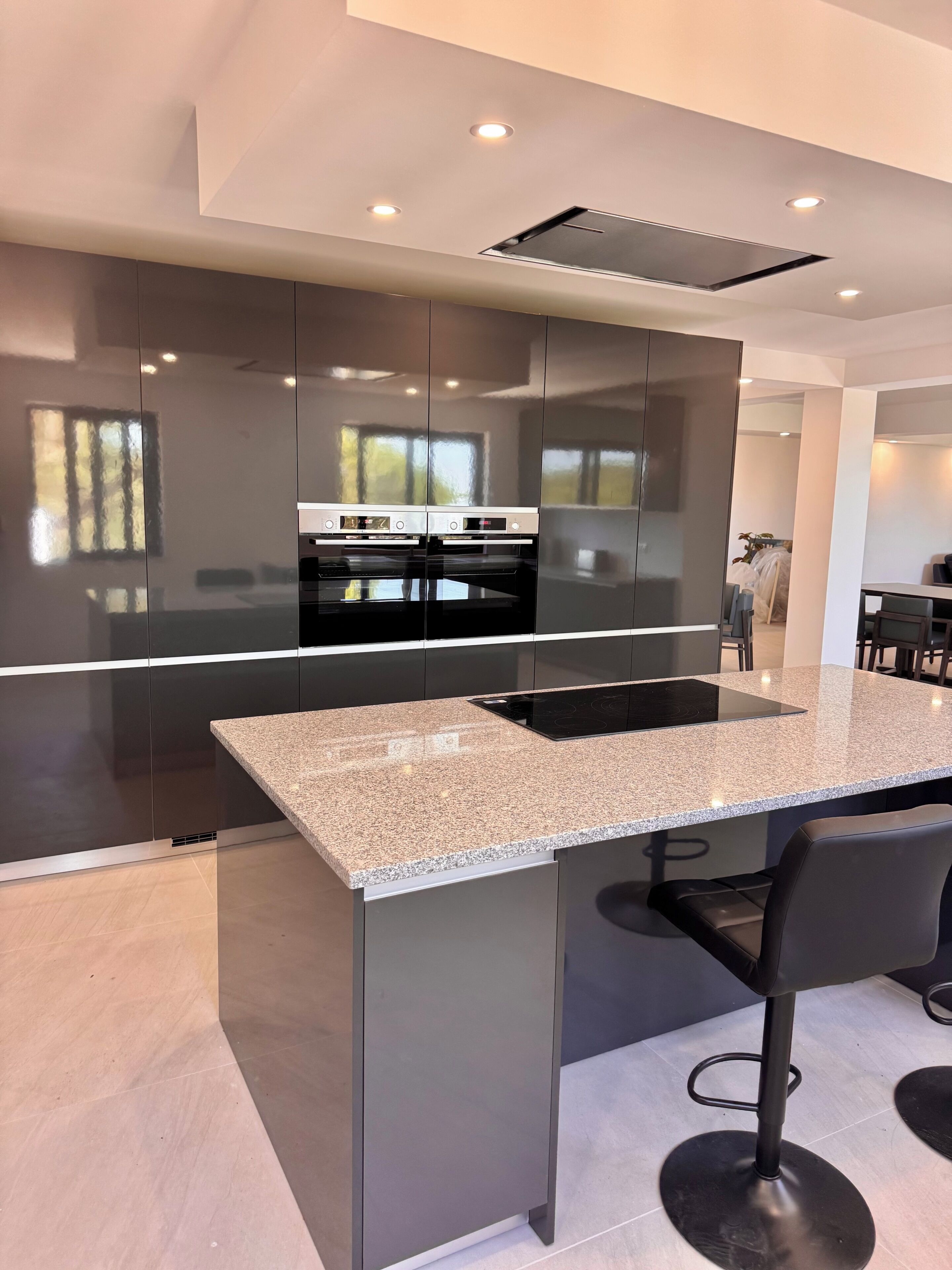 A modern kitchen with a central island, built-in appliances, and a dining area with bar stools.