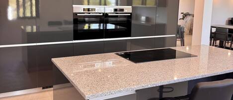 Una cocina moderna con una isla central, electrodomésticos integrados y un comedor con taburetes de bar.