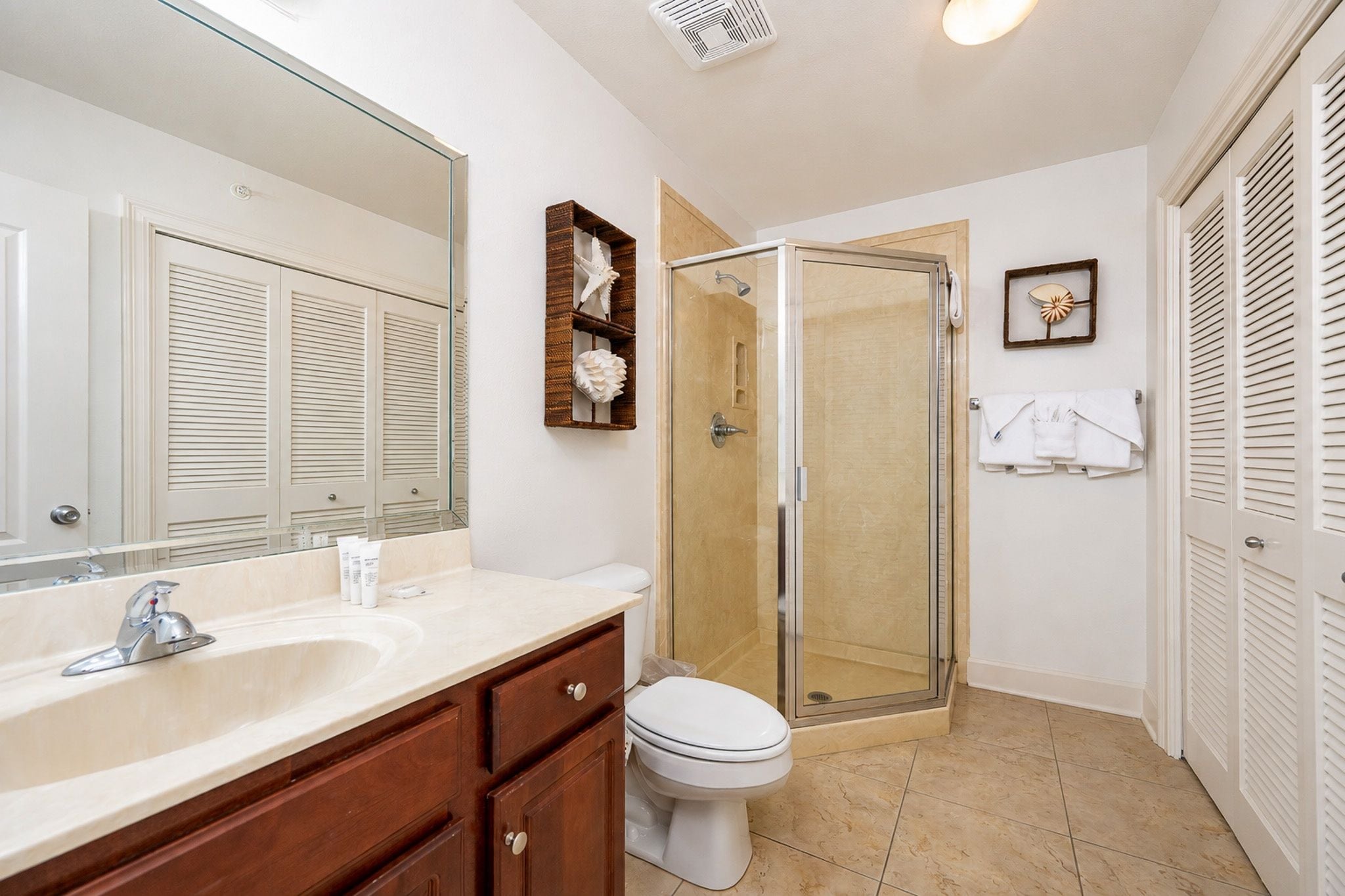 A bathroom with a large mirror, a sink with a faucet, a toilet, and a shower area with a glass door.