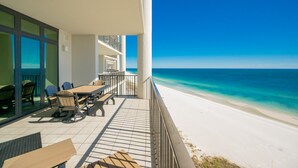 Un balcone con vista sulla spiaggia, mobili da esterno e cielo sereno.