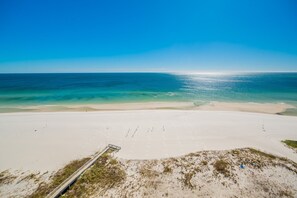 A beach with a clear sky, a sandy shore, and a boardwalk leading to the water. - The Oasis 1205 Formerly Phoenix West Ii 1205 3 Bedroom Condo (Orange Beach)
