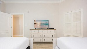Una camera d'albergo con due letti, una cassettiera e un quadro raffigurante una spiaggia.