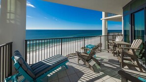 A balcony with a view of the beach, furnished with chairs and a table. - The Oasis 904 Formerly Phoenix West Ii 904 3 Bedroom Condo (Orange Beach)