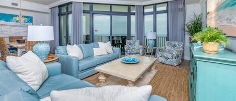 Un salon moderne avec un canapé bleu, une table basse et une grande fenêtre avec des rideaux.