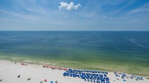 Luftaufnahme eines Strandes mit Reihen blauer Sonnenschirme und vereinzelten roten.