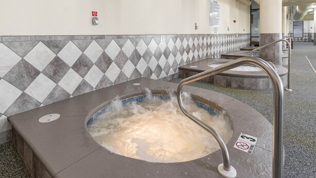 Ein Whirlpool mit Metallgeländer, eine mit Rautenmuster geflieste Wand und ein 'Nichtraucher'-Schild.