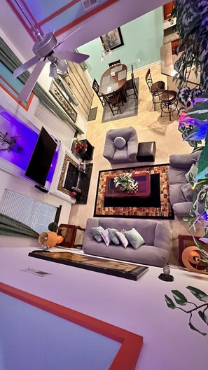 A modern living room with a sofa, coffee table, and a dining area with chairs and a table.