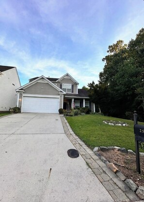 A residential driveway leading to a two-story house with a garage.