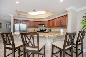 A kitchen with a central island, wooden cabinets, and a stainless steel refrigerator. - The Oasis 2402 Formerly Phoenix West Ii 2402 3 Bedroom Condo (Orange Beach)