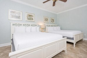 A bedroom with two beds, a ceiling fan, and framed artwork on the wall. - The Oasis 2402 Formerly Phoenix West Ii 2402 3 Bedroom Condo (Orange Beach)