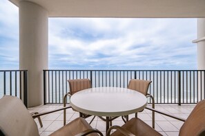 A round table with four chairs on a balcony with a railing, overlooking a body of water. - The Oasis 2609 Formerly Phoenix West Ii 2609 3 Bedroom Condo (Orange Beach)