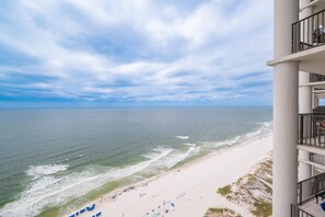 Blick auf einen Strand vom Balkon aus, mit blauem Himmel und Meer.