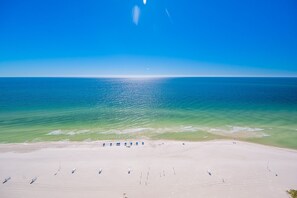 A beach with clear skies, calm sea, and a few umbrellas. - The Oasis 2306 Formerly Phoenix West Ii 2306 3 Bedroom Condo (Orange Beach)