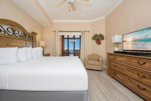A hotel room with a large bed, a television, a wooden dresser, and a view of the ocean through the window. - The Oasis 2306 Formerly Phoenix West Ii 2306 3 Bedroom Condo (Orange Beach)