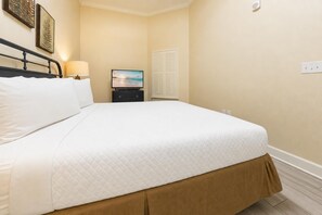 A hotel room with a bed, a nightstand, a television, and a window with blinds. - The Oasis 3006 Formerly Phoenix West Ii 3006 3 Bedroom Condo (Orange Beach)