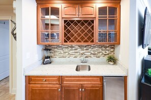 A kitchen with wooden cabinets, a stainless steel sink, and a tiled backsplash. - The Oasis 3208 Formerly Phoenix West Ii 3208 3 Bedroom Condo (Orange Beach)