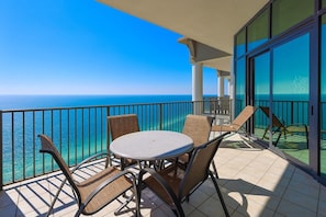 Ein Balkon mit rundem Tisch und Stühlen, Blick auf das klare, blaue Meer.