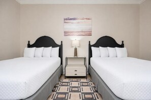 Une chambre d’hôtel avec deux lits, une table de chevet, une lampe et un tableau au mur.