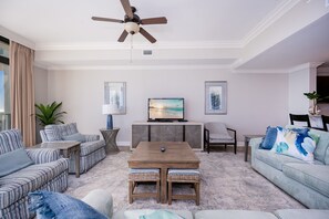 Un salon équipé d’un ventilateur de plafond, d’un téléviseur, d’une table basse et de deux canapés.