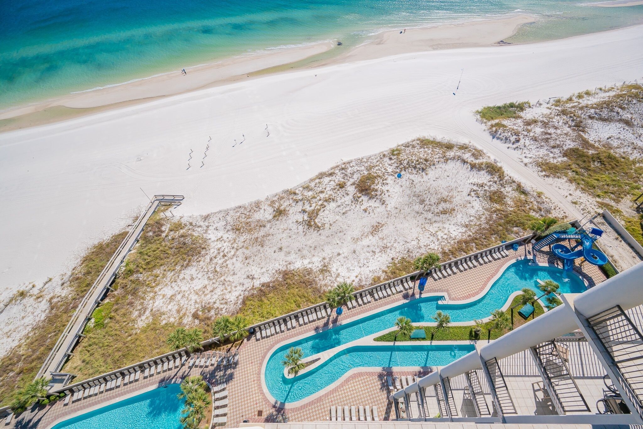Et resort med stort poolområde, en strand og et livredder tårn.