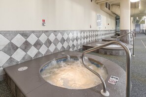 Un jacuzzi con baranda de metal, pared con mosaico formando un diseño de rombos y un cartel de 'No Smoking'.