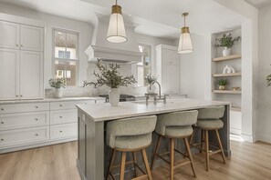 A modern kitchen with a central island, bar stools, pendant lighting, and built-in cabinetry. - Beso Del Sol 4 Bedroom Townhouse (St. George)