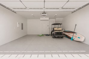 A garage with a golf cart, a paddleboard, and a ceiling-mounted projector. - Beso Del Sol 4 Bedroom Townhouse (St. George)