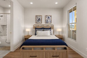 A bedroom with a wooden bed, two bedside lamps, a window, and two wall-mounted artworks. - Beso Del Sol 4 Bedroom Townhouse (St. George)