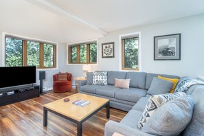 A modern living room with a grey sofa, a red armchair, a wooden coffee table, and a flat-screen TV. - Sunset Vista 3 Bedroom Condo (Telluride)